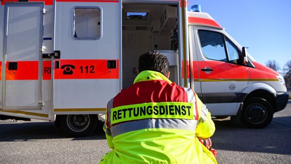 «Rettungsdienst» steht auf der Jacke eines Mannes vor einem Rettungswagen der Feuerwehr., © Jens Kalaene/dpa/Symbolbild
