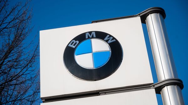 Vor einem Werk steht das Logo von BMW., © Christophe Gateau/dpa/Symbolbild
