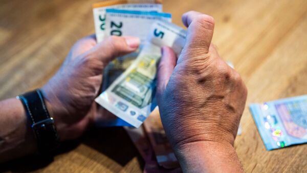 Ein Mann zählt Geld an einem Tisch., © Lino Mirgeler/dpa/Illustration