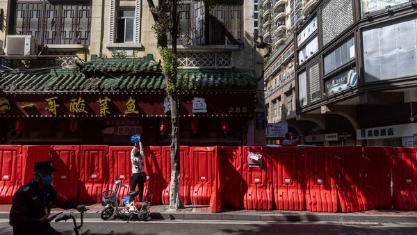 Ein Bewohner reicht Gegenstände über eine provisorische Absperrung in der Metropole Guangzhou, die errichtet wurde, um einen Wohnblock mit hohem Covid-19-Infektionsrisiko abzusperren., © Uncredited/CHINATOPIX/AP/dpa