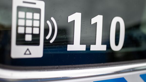 Der Nummer des Polizeinotrufs 110 steht auf der Scheibe eines Polizeifahrzeugs., © Daniel Karmann/dpa/Symbolbild
